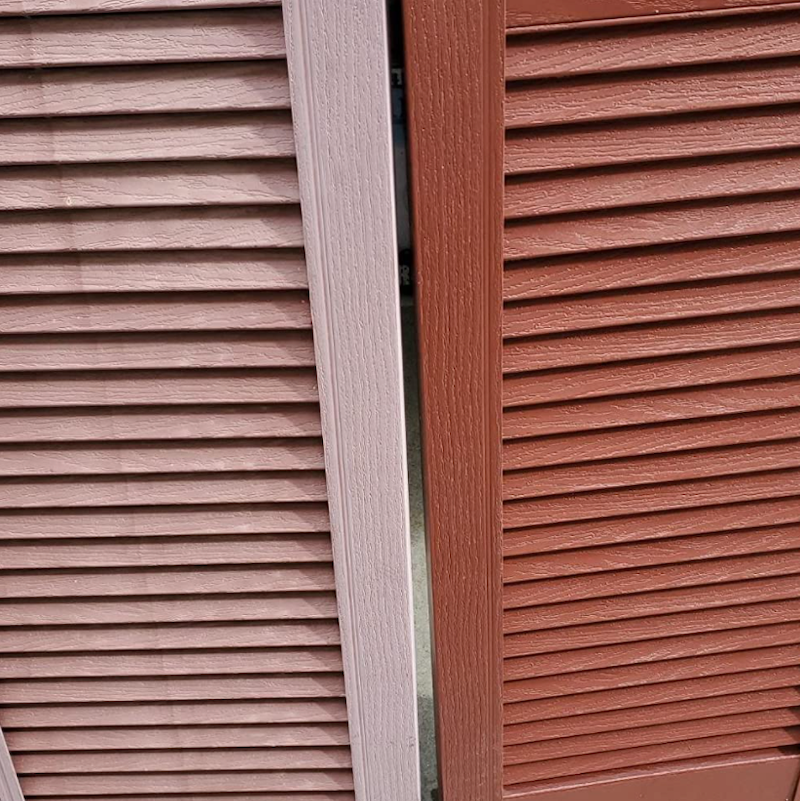 Two vertical wooden shutters in soft pink and deep brown, showcasing their slatted design with a slight gap between them.