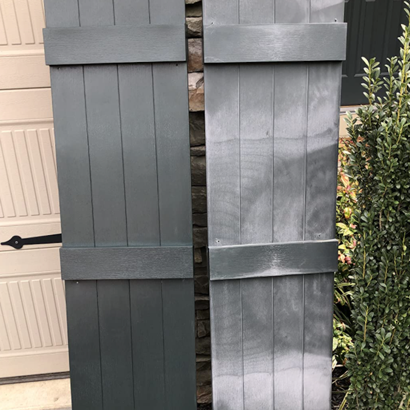 Two wooden shutters side by side: one painted teal and the other a distressed gray, next to a stone wall and greenery.