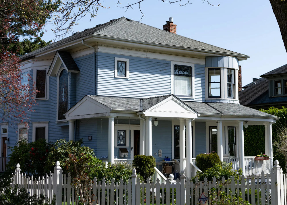 Front exterior of a modern multi-unit townhouse with blue siding, stone accents, and white garage doors.