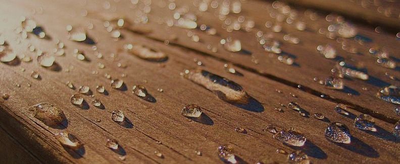 water droplets on surface of wood treated with Seal It Green Total Wood Armor Plant Based Wood Sealer